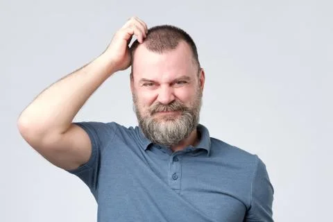 Confused man with beard scratching head looking at camera Stock Photos