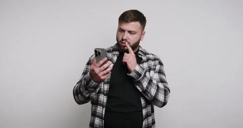 Confused man explores phone secrets in minimalist studio with thoughtful ex.. Stock-Footage 329110696