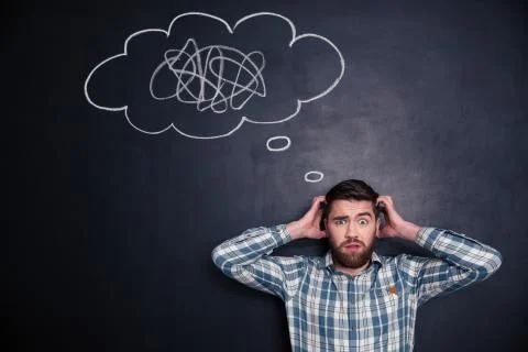 Confused man thinking about problem with black board behind him Foto stock