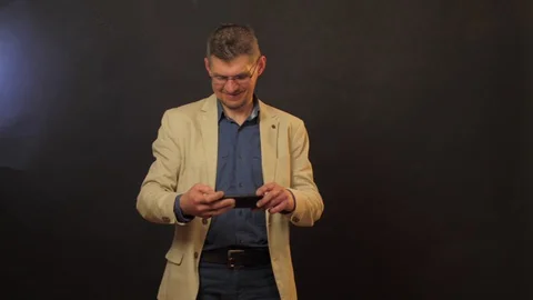Confused man types on black smartphone and hides into pocket Stock Footage 129304260