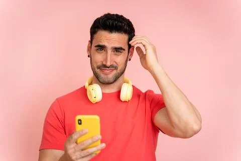 Confused man while using mobile phone in studio shot. Stock Photos