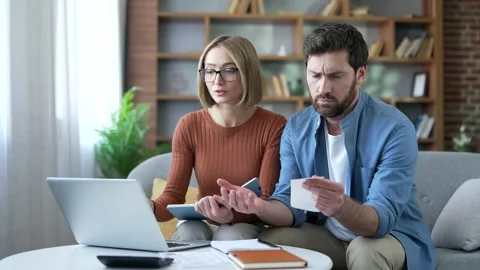 Confused married couple having difficulty doing household finances using  Stock Footage 337930401