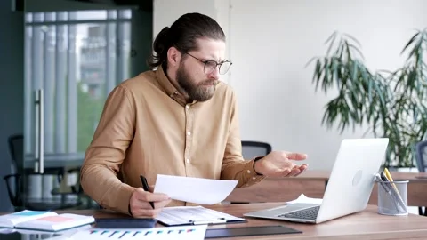 Confused puzzled businessman having difficulty with paperwork sitting in busines Stock Footage 321130333