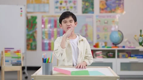 Confused Schoolboy Expressing Uncertainty at Classroom Desk Stock Footage 328083636