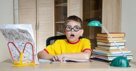 Confused schoolboy in funny glasses screaming near the huge stack of books. E Stock Photos