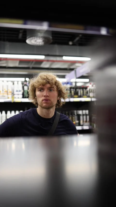 Confused shopper struggles to decide what product to buy in supermarket Stock Footage 345361041