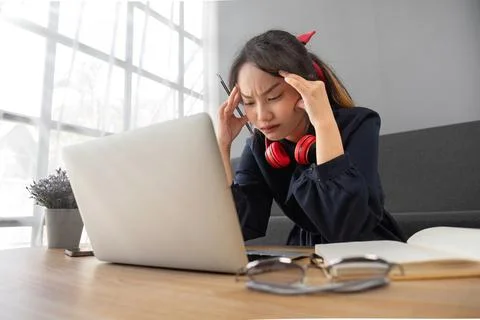 Confused student e-learning with laptop and headphones sitting on a couch in the Stock Photos