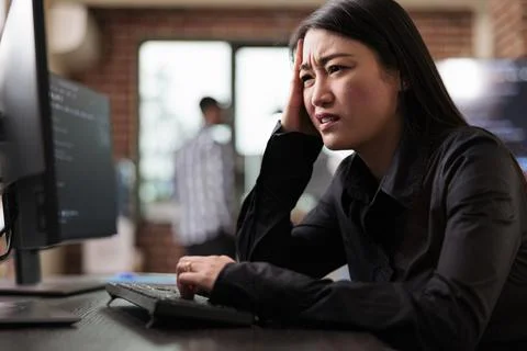 Confused tech engineer sitting at computer trying to solve network processing Stockfoto's