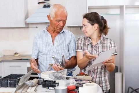 Confused woman with elderly father reading work manual on mixer tap Stock Photos