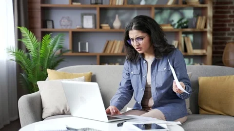 Confused young woman having difficulty doing household finances using Stock Footage 310790443