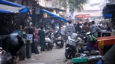 Congested lane with bikes parked, people walking next to dingy shops, Mumbai Stock Footage 329098571