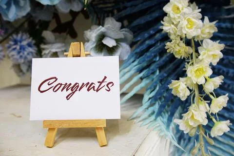 Congrats text write on paper card with wooden easel and flowers decoration .. Stock Photos