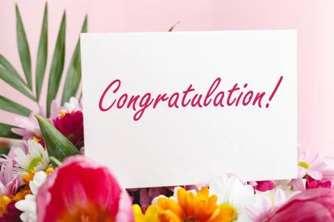 Congratulation text on gift card in flowers bouquet on pink background. White Foto stock