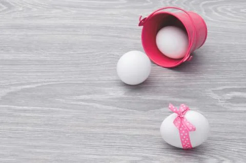 Congratulations on Easter. Eggs scattered on the table with a pink bucket. Stock Photos
