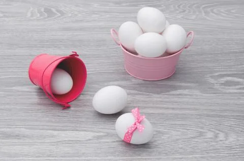 Congratulations on Easter. Eggs scattered on the table with a pink bucket. Stock Photos