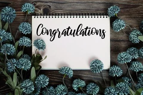 Congratulations text on notepad with flower decoration on wooden background Stock Photos