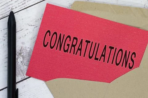 Congratulations text on red card with envelope and pen on wooden table. Stock Photos