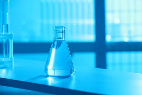 Conical flask with blue liquid on table indoors, color toned effect. Space .. Stock Photos