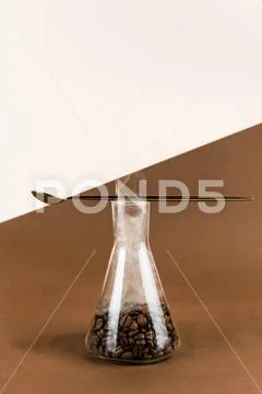 Conical flask with coffee beans on brown and light background with golden spo Stock Photos