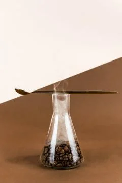 Conical flask with coffee beans on brown and light background with golden spo Stock Photos