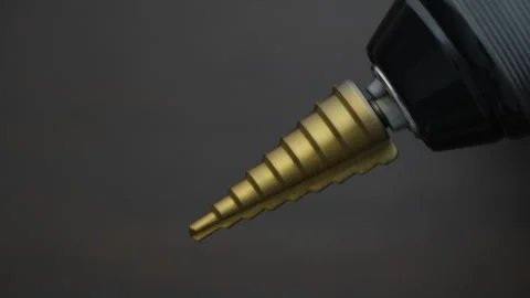 Conical step drill clamped in electric screwdriver rotates, close up Stock Footage 310163707