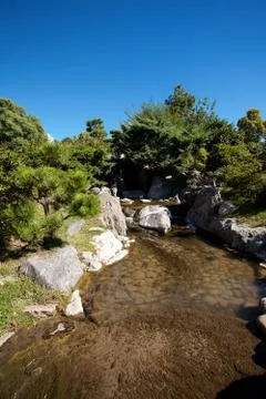 Coniferous trees, rocks and a waterfall on a background of blue sky Foto stock