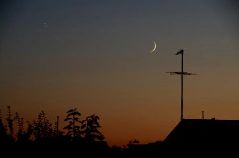 Conjunction between Moon and Venus seen in the evening in urban surroundings. Stock Photos