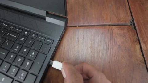 Connect and plug in USB type-C cable on to Laptop Port on Wooden Surface Stock Footage 311796242