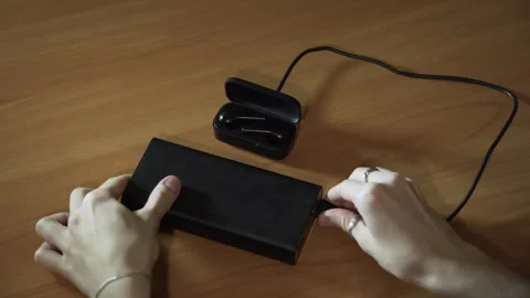 Connect the USB cable to an external battery to charge the wireless headphones Stock-Footage 256241858