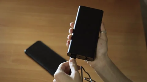 Connect the USB cable to an external Power Bank battery to charge smartphone Stock-Footage 256056424