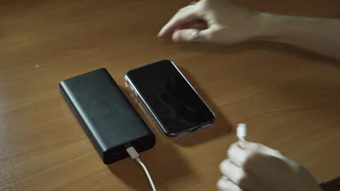 Connect the USB cable to an external Power Bank battery to charge smartphone Stock Footage 256056452