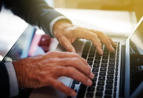 Connected to his work commitments. a businessman using a laptop at his work desk Stock Photos