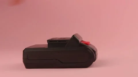 Connecting the battery to a screwdriver on a pink background Stock Footage 135319214