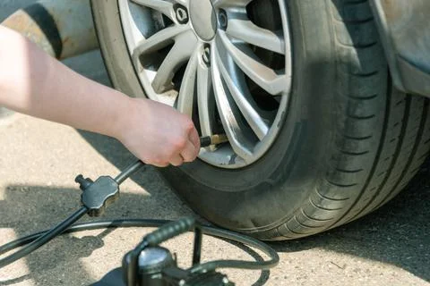 Connecting the compressor to the car tire, checking the air pressure and fill Stock Photos