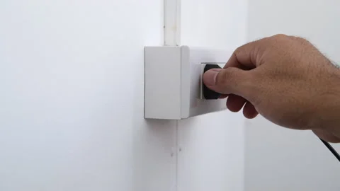 Connecting electrical power plug with hand a power socket on a interior wall Stock Footage 171529330