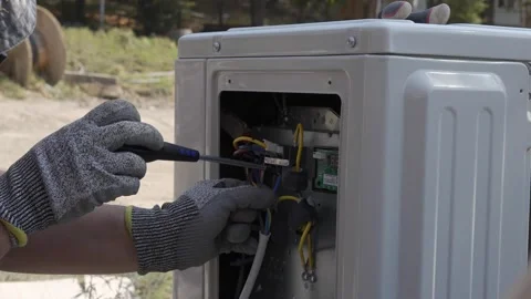 Connecting electrical wires with a screwdriver inside an outdoor air conditioner Stock Footage 346245411