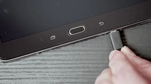 Connecting a micro USB cable to an old black tablet. Stock Footage 251857592