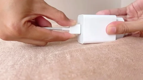 Connecting a USB cable into the white phone charger Stock Footage 146248758