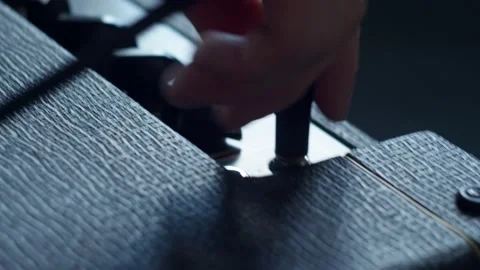 Connecting the wire to the combo amplifier and switching the knobs for its 스톡 동영상 156256993