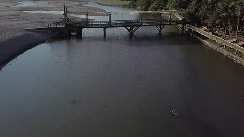 Connecting wooden bridge in between two banks above the river aerial footage Stock Footage 100692802
