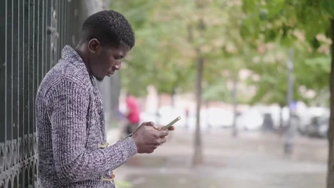 Connection, communication - young black man types quickly on his smartphone Stock Footage 240332801
