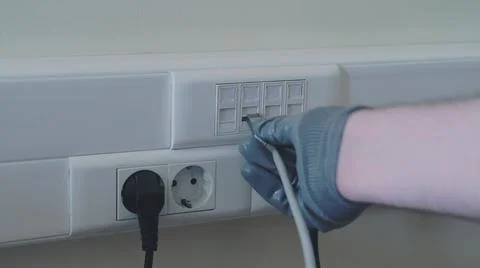 Connection to a computer network in the office, a gloved hand holds a cord fo Stock Photos