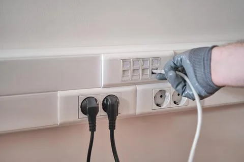 Connection to a computer network in the office, a gloved hand holds a cord fo Stock Photos