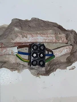 Connection of two three-core cables in a contact group on a wall, close-up Stock Photos