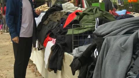 Conscious Consumer Choosing Used Clothes at Flea Market Supporting Circular Stock Footage 330169044