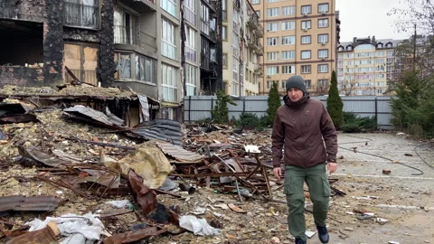 Consequences of the war in Irpen. A man walks near a destroyed blackened house Stock Footage 241174171