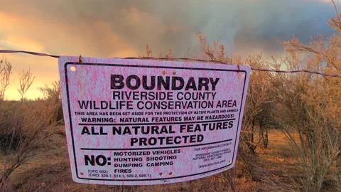 Conservation boundary sign blows in wind as large wildfire burns in the Stock Footage 218967984