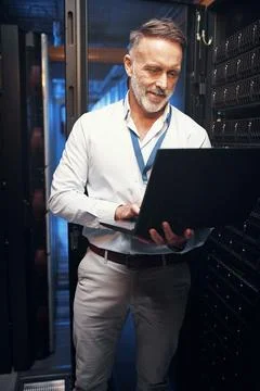 Consider it sorted. a mature man using a laptop while working in a server room. Stock Photos