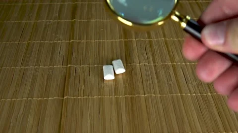Considers gum under a large magnifying glass in a collection of two pieces Stock Footage 132219657