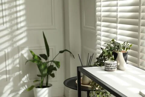 Console table with different decor near window indoors, closeup. Interior d.. Stock Photos